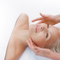 A beautiful middle-aged woman laying on a treatment bed receiving a facial treatment